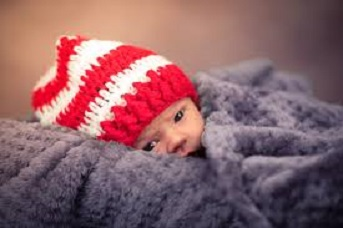 baby with a crocheted cap wrapped in a crocheted blanket